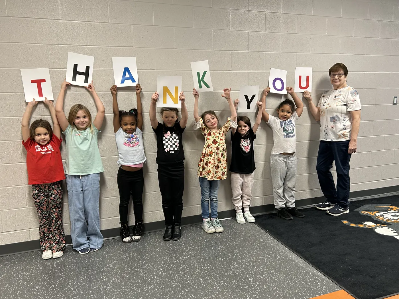 Seven students and a mentor holding letters overhead that spell THANK YOU
